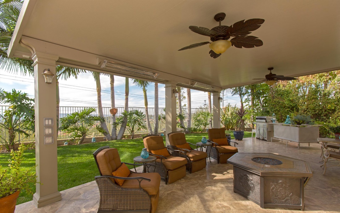 Covered Patio with Outdoor Cushioned Chairs Circling a Fire Pit and a Fan with Leaf-Shaped Blades Overhead  